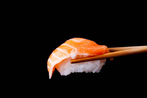 salmon sushi by wooden chopsticks - sushi sashimi nigiri salmon imagens e fotografias de stock
