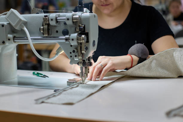 close-up of the process of sewing fabric by a woman in production - garment factory imagens e fotografias de stock