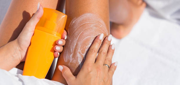 Protection from the sun. A woman applies a cream before tanning. crema de protección solar para el cuidado de la piel. primer plano de las piernas de una mujer aplicando loción de protección solar antes de tomar el sol. una hermosa mujer de piel oscura pone crema en una pierna bronceada en una playa tropical.