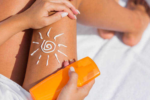 Protection from the sun. A woman applies a cream before tanning. crema de protección solar para el cuidado de la piel. primer plano de las piernas de una mujer aplicando loción de protección solar antes de tomar el sol. una hermosa mujer de piel oscura pone crema en una pierna bronceada en una playa tropical.