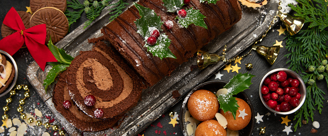 Chocolate yule log on dark background. Traditional dessert of Christmas time. Top view, panoramma