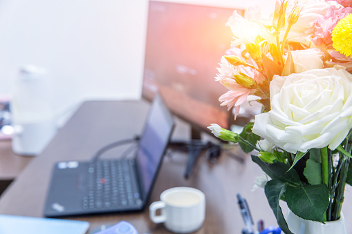 Flowers and laptop on table, empty office