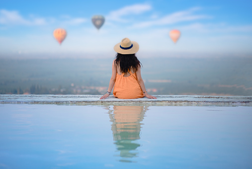 Beautiful traveller tourist girl is  watching hot air balloons in Pamukkale travertine pools in  Denizli, Turkey