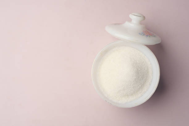 istock white sugar and spoon in a container on black background, 1414908762