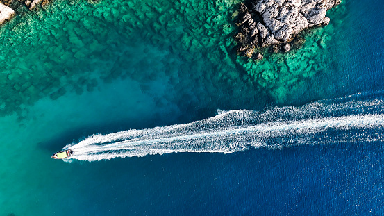 Luxury speed boat floating in open sea at summer, Yacht sailing in sea at hot summer day, Seashore of Mediterranean Sea at summer, Cruise speed boat floating in sea along rocky mountain coastline of Mediterranean Sea