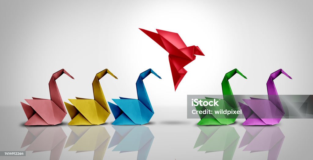 Innovative Thinker Concept Innovative thinker concept and new idea thinking as a symbol of revolutionary innovation and inspiration metaphor as a group of paper swans and a game changer origami bird in flight. Origami Stock Photo