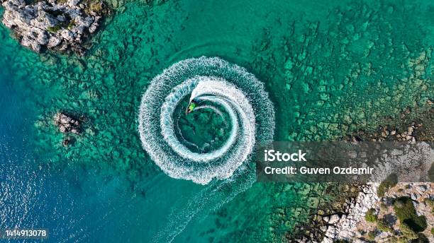 Zoom Out Amazing Aerial View Of Man Driving A Personal Watercraft In The Ocean Creating A Straight Down Circular Patternamazing Summer Background Water Color And Beautiful Bright Clear Turquoise Adventure Day On Tropical Beach Spinning Speed Boat Stock Photo - Download Image Now
