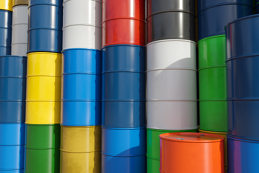 Multicolored metal barrels with oil and chemicals on the production site.