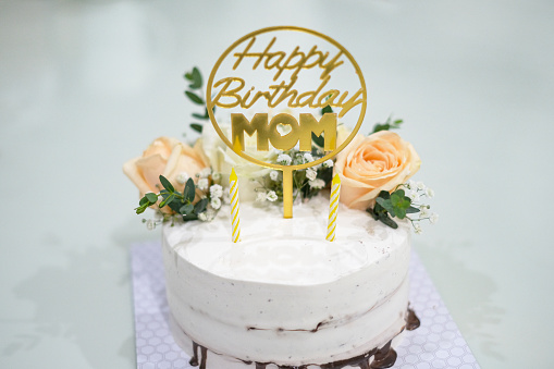 Close-up shot of gold happy birthday cake topper for mother with Rose flower decoration