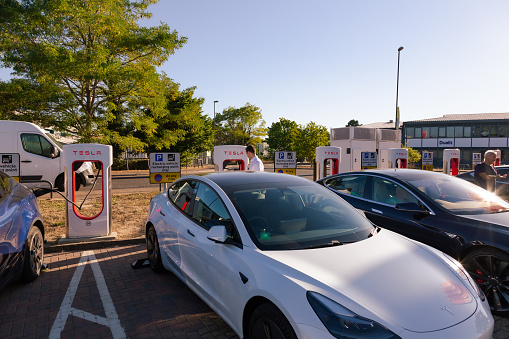 Crawley, UK - 10 August, 2022: Color image depicting a man charging his electric vehicle at a Tesla charging station in Crawley, a town in the southeast of England. Room for copy space.