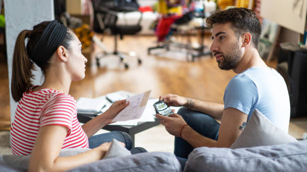istock Couple calculating bills at home using calculator.  Couple checking bills and documents while calculating finances sitting in the living room. Man and woman at home analyzing their finance with documents. 1414921466