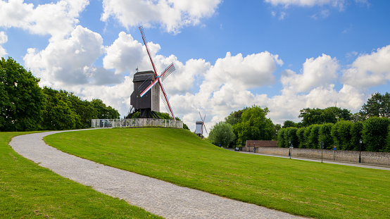 Brugge, Belgium - July 4, 2022: Old windmill in Bruges on a sunny day in summer, blue sky, clouds