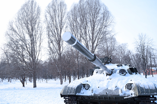 View of the cannon of the tank in the snow on nature in the forest. Military equipment. War in winter