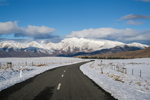 Lake Ohau road leading towards snow-covered mountain ranges, Twizel, South Island.