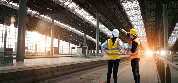 El equipo técnico de ingenieros revisa y analiza un proyecto de construcción de estaciones de ferrocarril sin terminar con software y plano, Diseño y planificación de la construcción, Trabajo en equipo. photo