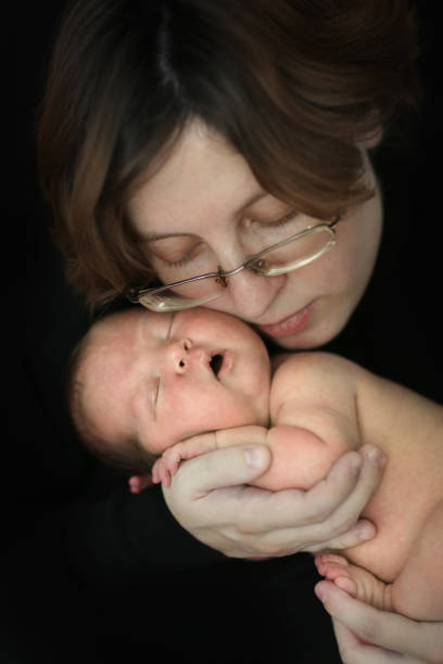 istock brunette mom and newborn baby on  dark background 1414925921
