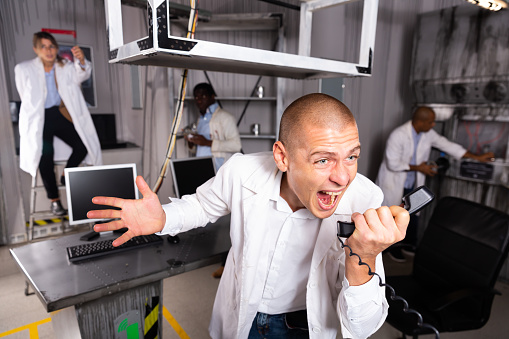 Expression american man in quest room with colleagues, trying to find solution of conundrum. Business challenge solving concept