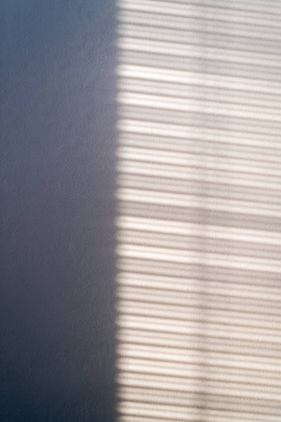 istock Light passes through the louvered shutters and falls on the wall forming a striped silhouette. 1414932981