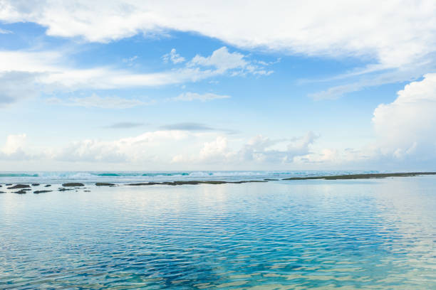 Ocean, white sand beach and blue sky with fluffy clouds.