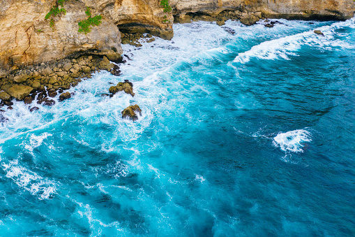 Bali, aerial shot of the blue ocean and beach full of big rocks.