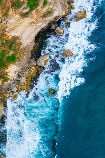 istock Ocean waves hitting a rocky beach and cliffs. View from above. 1414933534