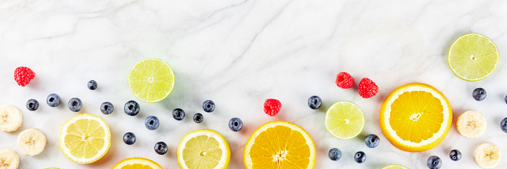 Fresh summer food menu banner. Fruit slices, shot from above on a white marble background with a place for text
