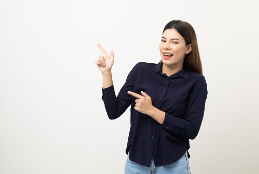 Young beautiful woman pointing finger to copyspace. Happy cheerful female on isolated white background. Pointing to blank space for advertise text.