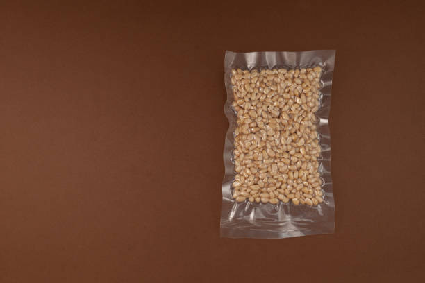 Cedar nuts. Peeled pine nuts in transparent vacuum package.  Brown background, copy space.