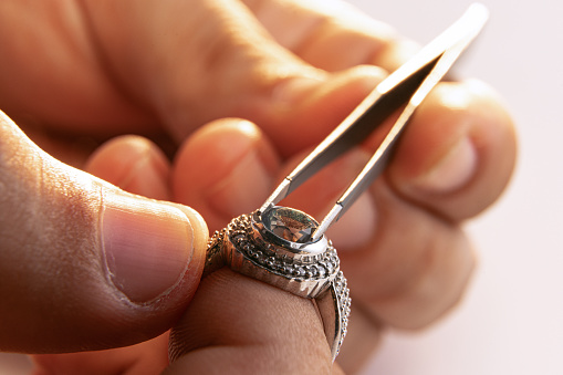 Ring repair process. Closeup hands of jeweler at work in jewelry. Desktop for craft jewelry making with professional tools. Concept of job, business, beauty, art and ad.