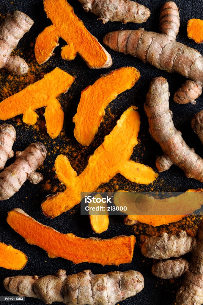 Fresh turmeric, curcuma roots on a black background Turmeric roots and curcuma powder, close up view. An excellent spice and healing agent Turmeric Stock Photo