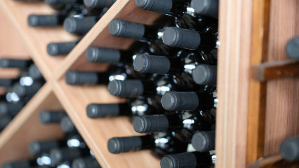 red wine bottles stacked on wooden racks closeup - wine wine bottle cellar basement imagens e fotografias de stock