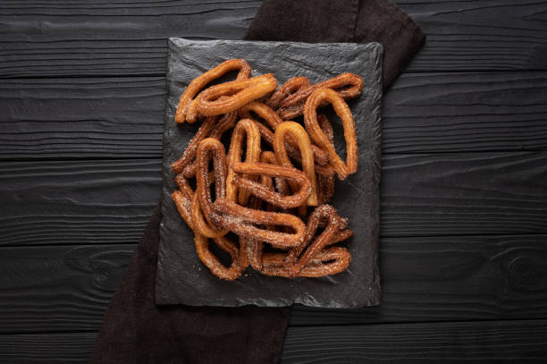 istock Homemade churros with chocolate on a dark wooden rustic background. 1414945151