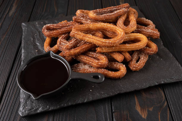 istock Homemade churros with chocolate on a dark wooden rustic background. 1414945177