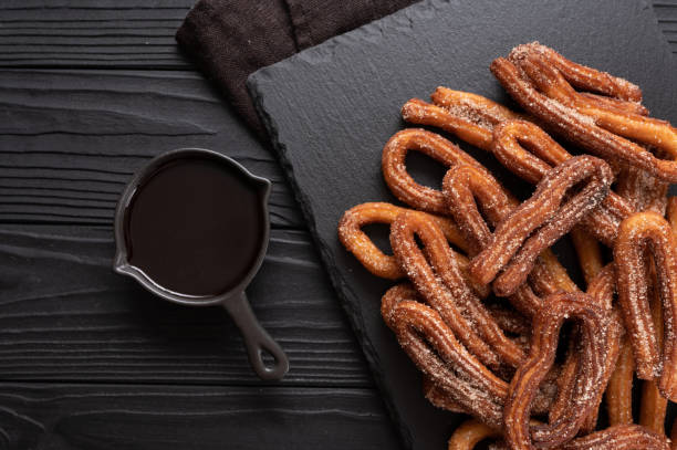 istock Homemade churros with chocolate on a dark wooden rustic background. 1414945418