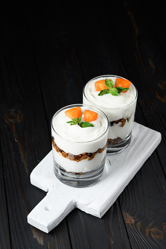 Homemade layered dessert with fresh apricot, cream cheese or yogurt, granola on rustic background.