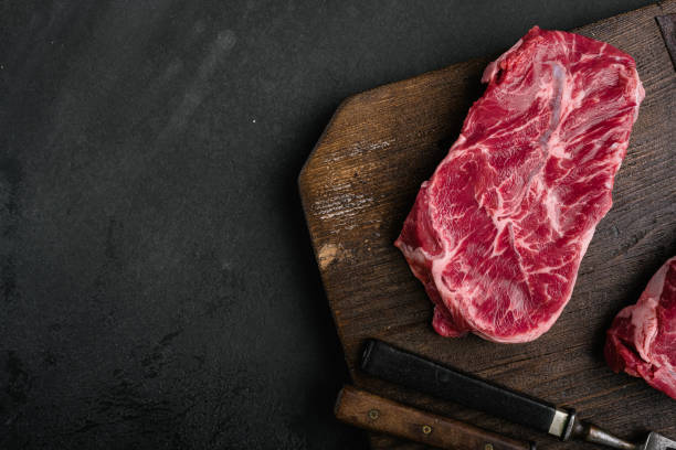 istock Raw fresh meat Top Blade steaks, on black dark stone table background, top view flat lay, with copy space for text 1414945860