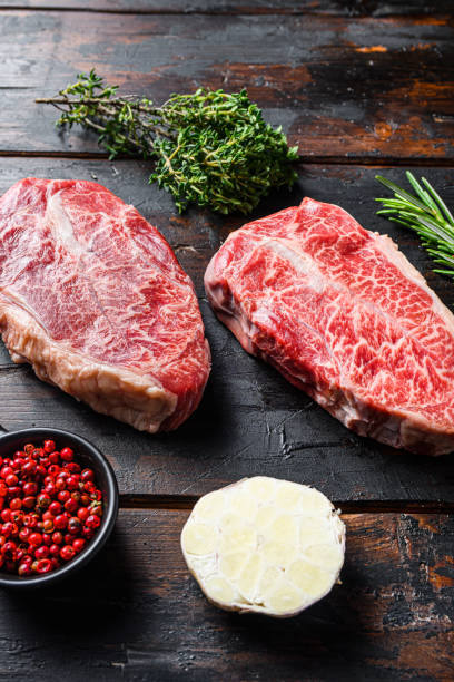 Boneless Top Chuck Steak, bio raw meat, marbled Flat Iron beef over old wood table background. Side view