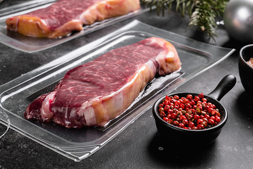 Raw steak with Christmas tree decorations set, on black dark stone table background