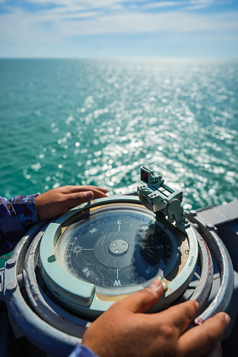 Military personnel reads the compass on a military ship sailing on the sea.