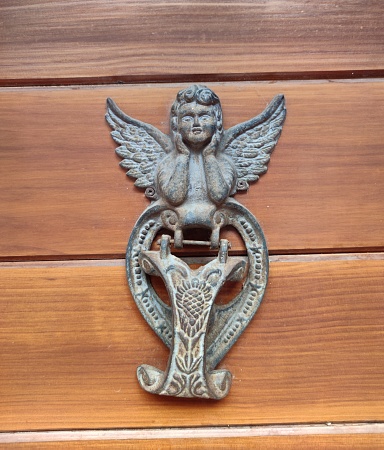 An iron knockdoor on an ancient wood door, beautiful angel