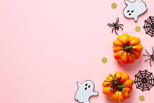 istock Happy Halloween concept. Flat lay composition with cute ghosts, orange pumpkins, spiders, confetti on pink background. Top view, copy space. 1414953943