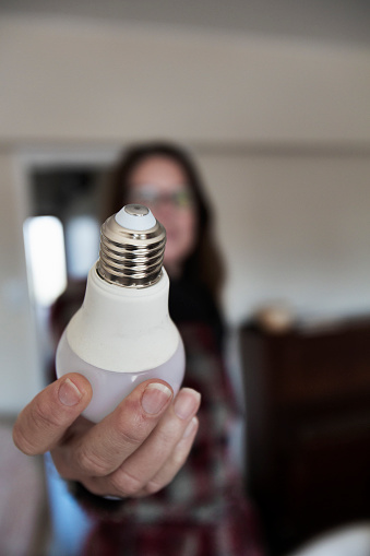 A woman replaces a light bulb on a ceiling light at home