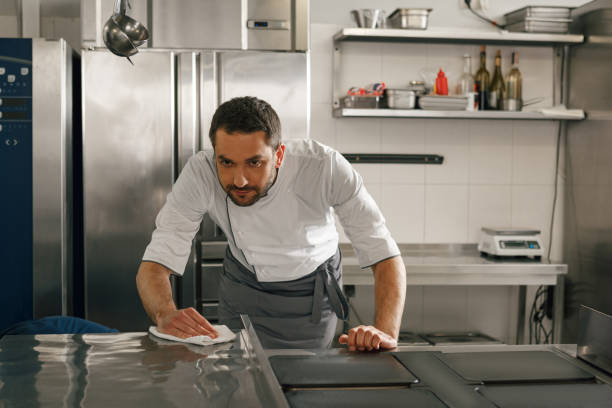 istock Young handsome male chef cleaning his workplace on kitchen in restaurant 1414954599
