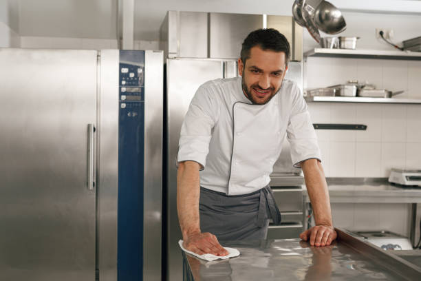 istock Young handsome male chef cleaning his workplace on kitchen in restaurant 1414954645