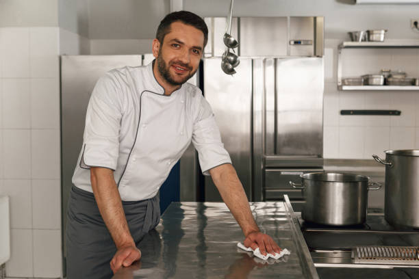 istock Young handsome male chef cleaning his workplace on kitchen in restaurant 1414954649