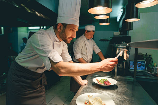 istock Handsome Chef cook in uniform checking the order at the restaurant kitchen 1414955470