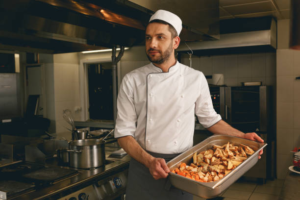 istock Chef holding tray with baked vegetables while standing in the kitchen of restaurant 1414955520