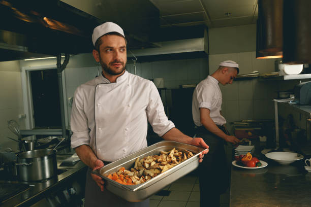 istock Chef holding tray with baked vegetables while standing in the kitchen of restaurant 1414955526