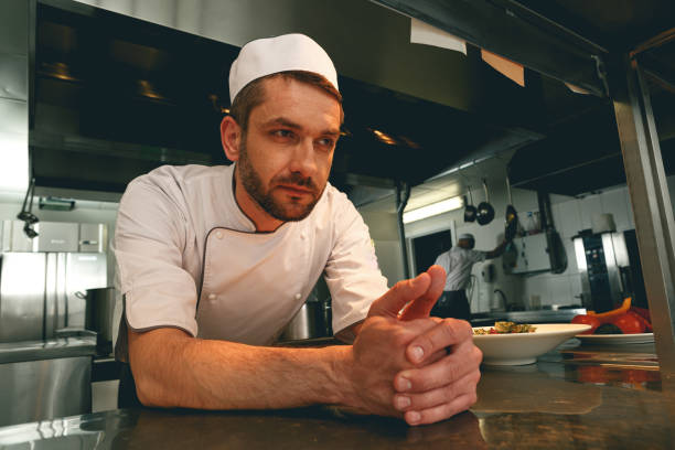 Tired chef on kitchen restaurant waiting for a new order Tired chef on kitchen restaurant waiting for a new order. High quality photo restaurant labor union stock pictures, royalty-free photos & images