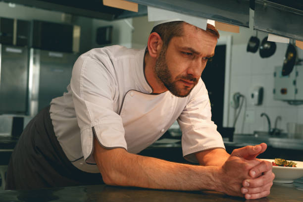 Tired chef on kitchen restaurant waiting for a new order stock photo